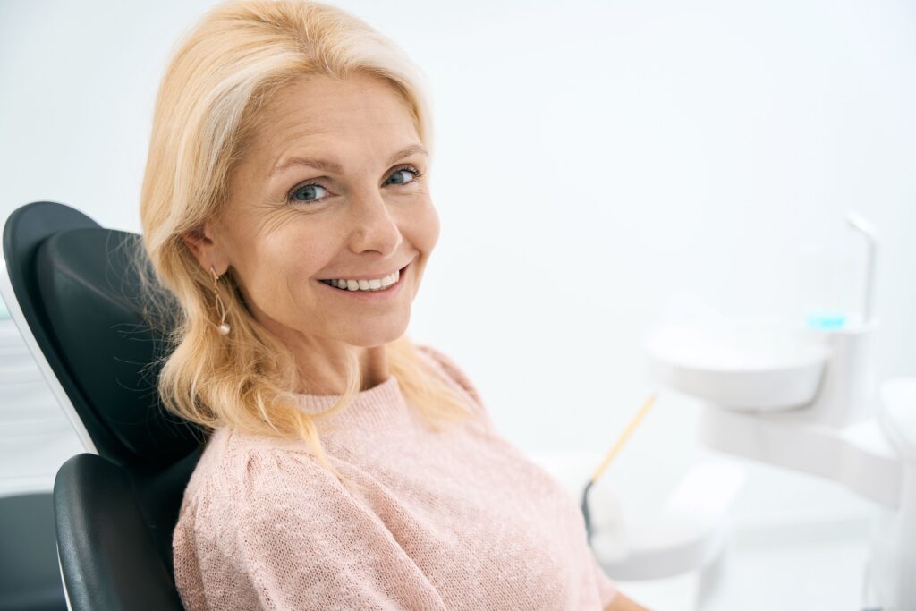 Smiling woman in the dental chair before a tooth extraction at All Smile Care