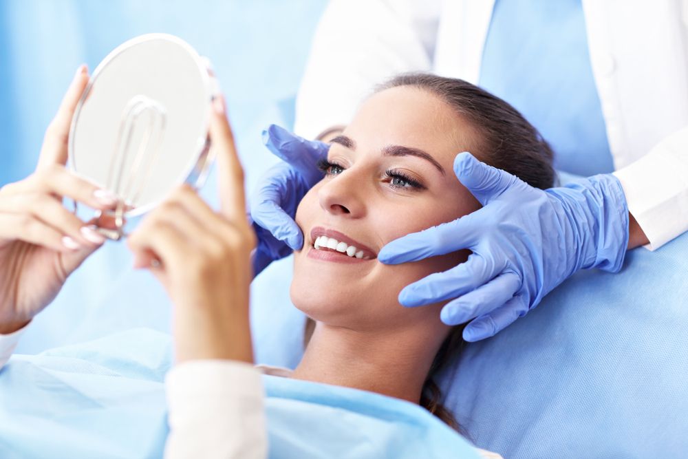 Woman checking her teeth whitening results in a dental mirror