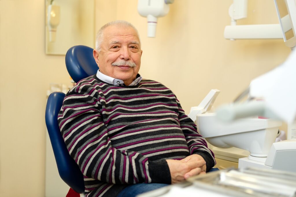 Smiling elderly man during a dental exam at All Smile Care in Lowell, MA