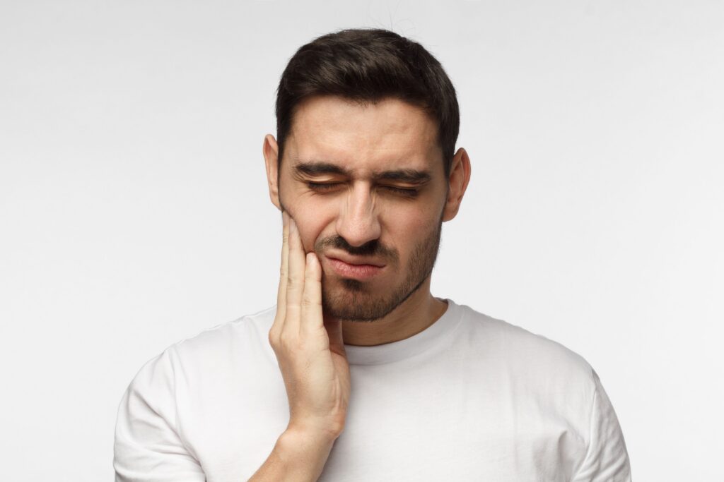 Man holding his jaw in pain after a dental injury