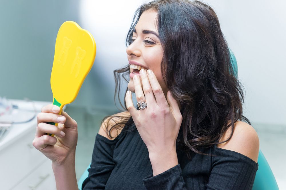 Woman checking her smile after a tooth contouring procedure