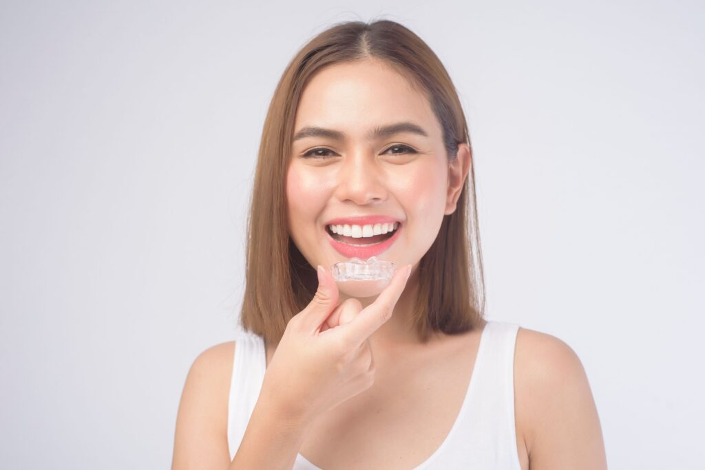 Woman placing a clear Invisalign aligner over her teeth