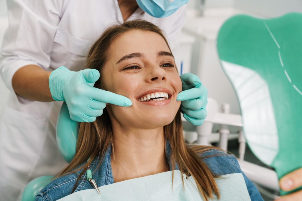 Woman admiring her whiter smile in a mirror after professional teeth whitening